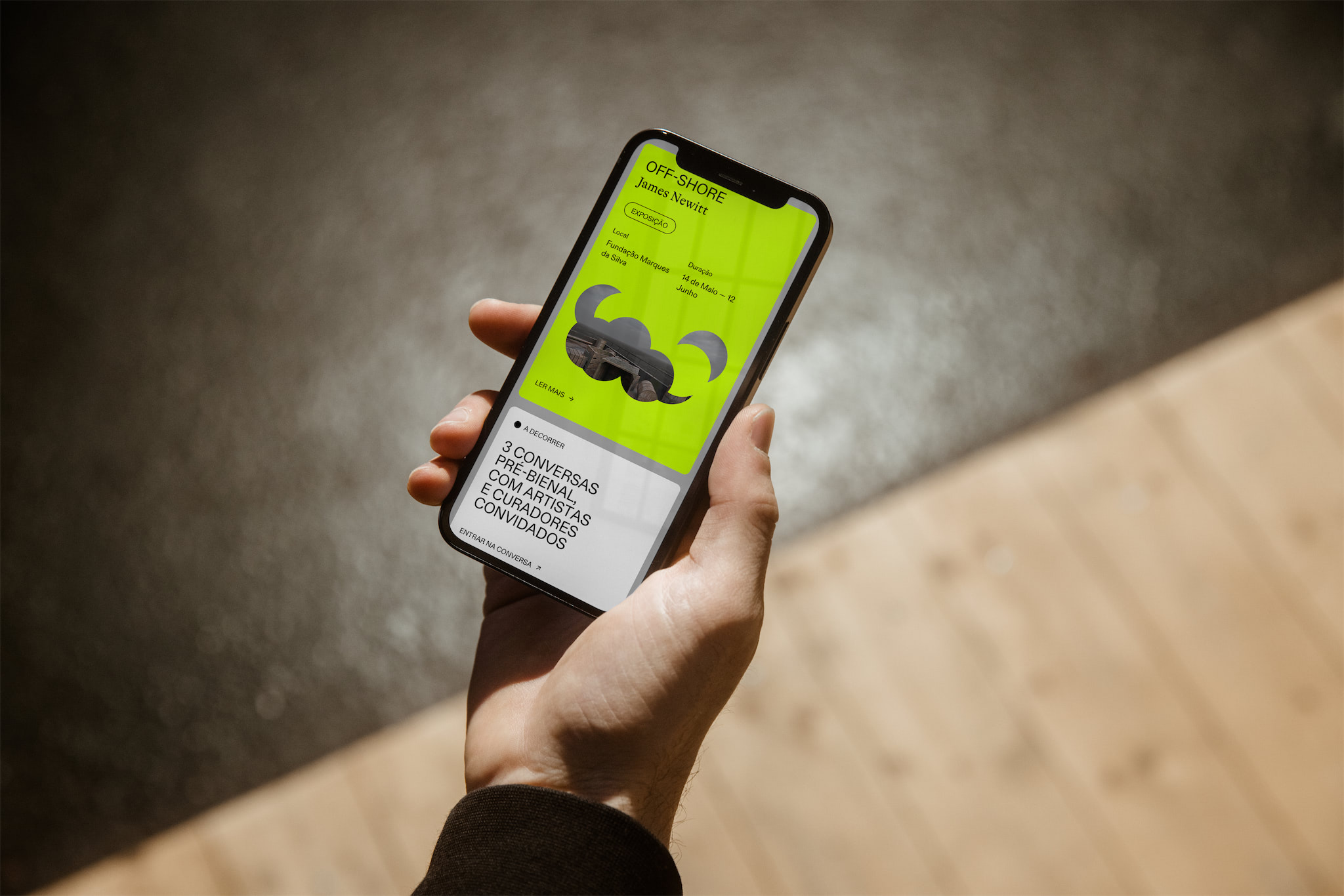 An iPhone in a hand with the website loaded.
